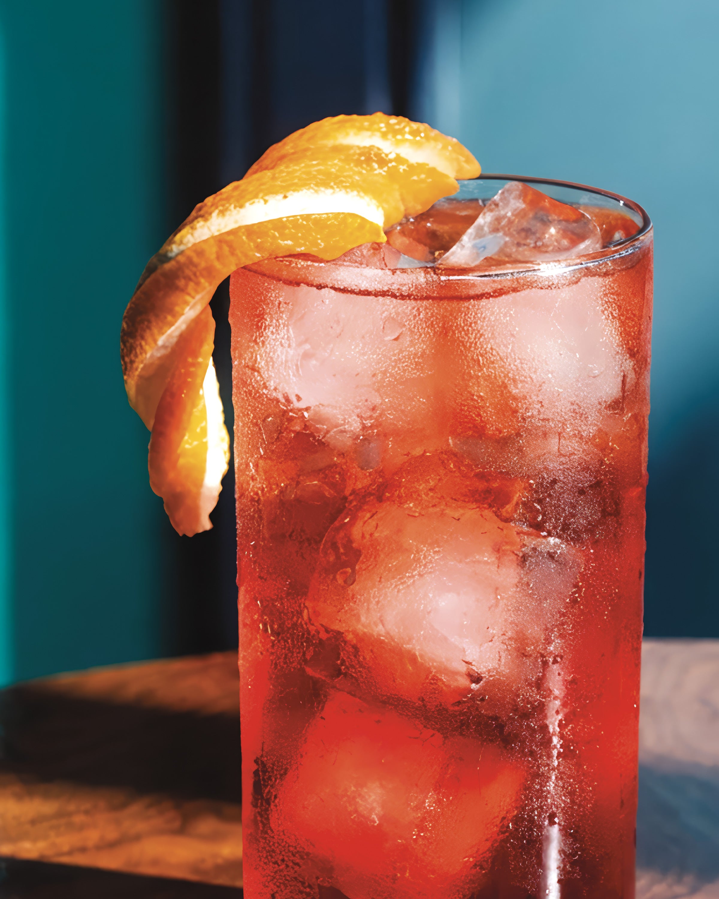 Campari cocktail with ice and an orange slice on a blue background